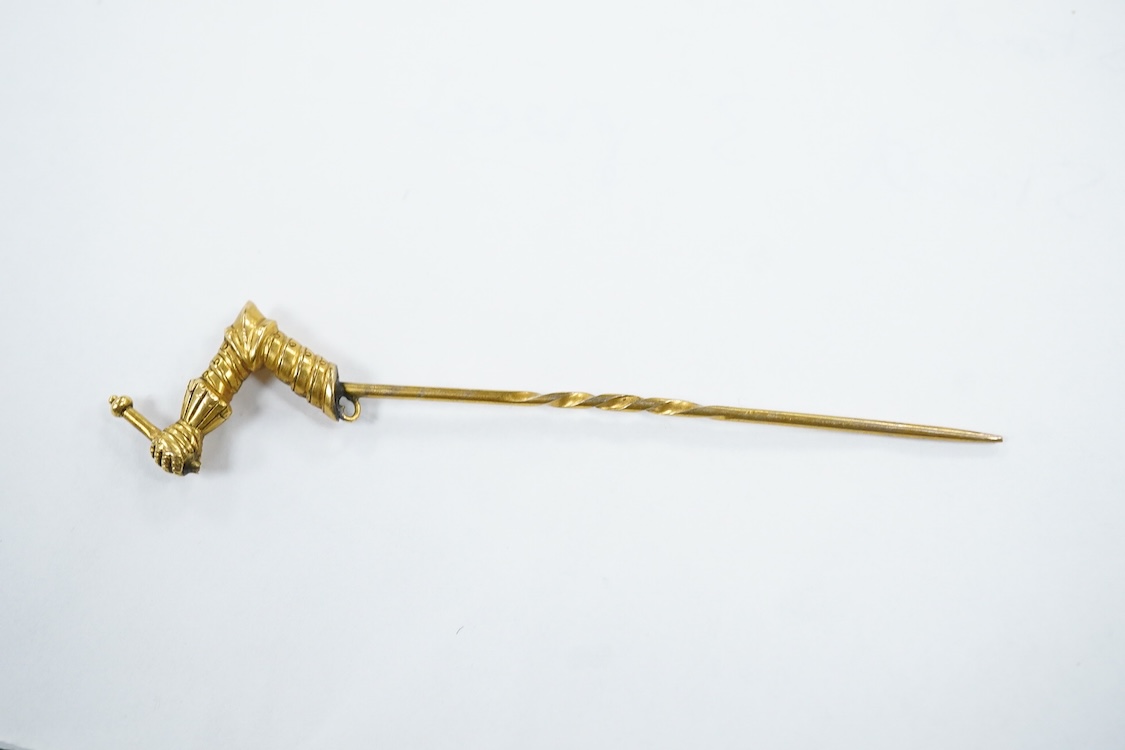 A yellow metal stick pin, the terminal modelled as a Knight's arm holding a scroll(a.f.), 79mm, together with two pairs of yellow metal and gem set ear clips including 9ct and opal doublet.